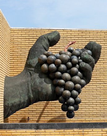 Escultura de Cándido Pazos sobre una mano gigante que sostiene un racimo de uvas; y que se encuentra en el Museo del Vino de Vivanco.